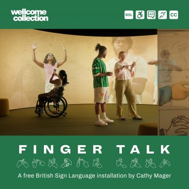 Finger Talk exhibitions space featuring a large projection screen. Two people standing and signing and one wheelchair user holding a mobile phone to take a photo.